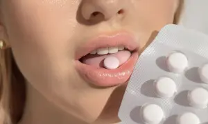 Usta z tabletką na języku i opakowaniem. Probiotyk na nieprzyjemny zapach z ust dla świeżego oddechu.