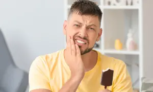 Mężczyzna z bólem zęba, trzymający loda. To klasyczne objawy nadwrażliwości zębów.