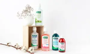 Wybierasz, czym płukać dziąsła? Cztery płyny GUM: ActiVital, Original White, SensiVital+ i Paroex, obok delikatnych kwiatów, sugerują różne opcje pielęgnacji.