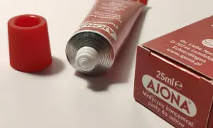 Pasta Ajona, medyczny koncentrat do zębów. Zastanawiasz się nad jej stosowaniem i potencjalnymi skutkami ubocznymi? Tubka i opakowanie na białym tle.