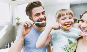 Rodzina myje zęby. Tata, córka i mama szczotkują zęby, przygotowując się na dzień. Czy mycie zębów przed czy po śniadaniu?