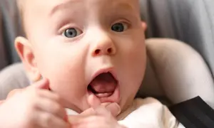 Maluch z otwartymi ustami pokazuje pierwsze zęby w 4 miesiącu.
