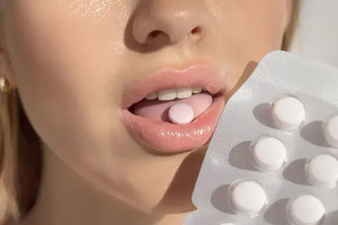 Usta z tabletką na języku i opakowaniem. Probiotyk na nieprzyjemny zapach z ust dla świeżego oddechu.