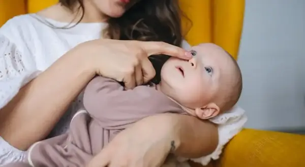 Mama delikatnie dotyka noska dziecka, które ma katar przy ząbkowaniu.