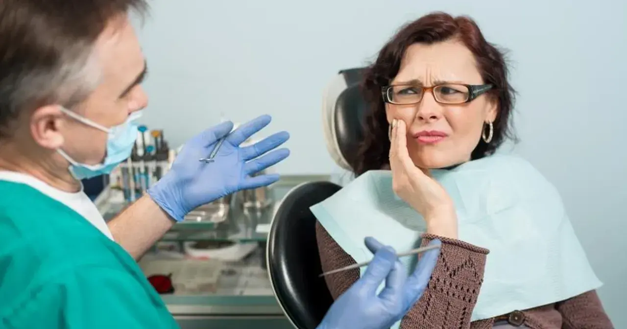 Kobieta z bólem zęba u dentysty, który pokazuje narzędzia. Wygląda na to, że czeka ją leczenie zatrucia zęba.