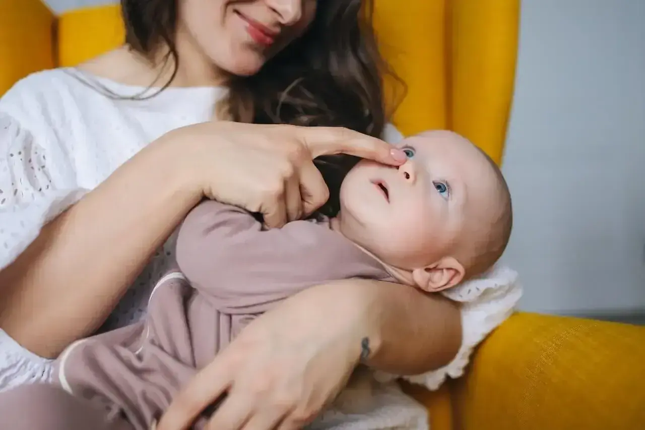 Mama delikatnie dotyka noska dziecka, które ma katar przy ząbkowaniu.